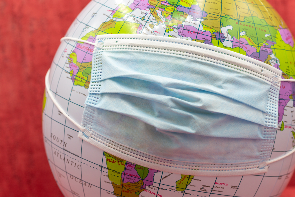 Globe dengan topeng klinis pada saat covid-19 dan korona dengan topik pemesanan liburan, perjalanan, penguncian, dan keamanan saat pandemi